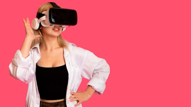 Beautiful girl in VR glasses on a pink background in virtual reality