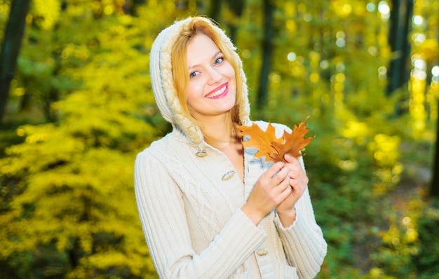 Beautiful girl walking in autumn park. Smiling woman with yellow leaves. Female enjoying autumn weather. Sunny day.