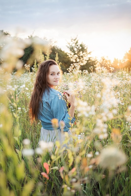 Beautiful girl walking on field on summer with wildflowers