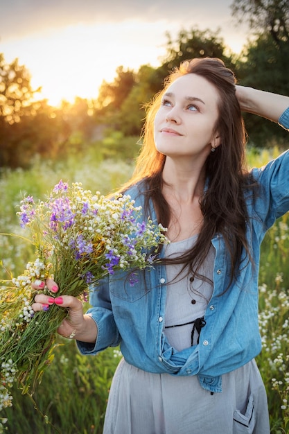 Beautiful girl walking on field on summer with wildflowers