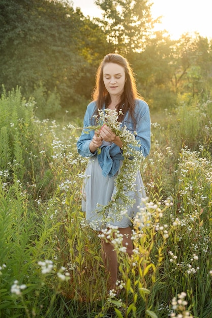 Beautiful girl walking on field on summer with wildflowers