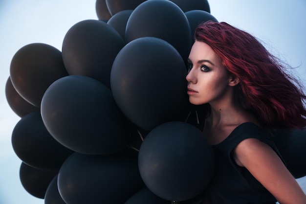 Beautiful girl walking with black balloons