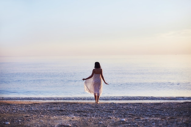 Beautiful girl walks along the beach on a Sunny day. Slender sexy woman resting on the sea