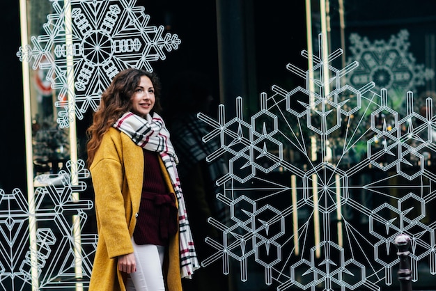 A beautiful girl walks the streets of Paris and looks at the beautiful New Years windows