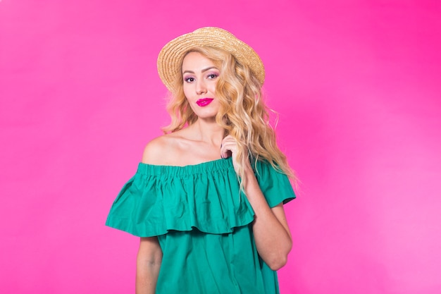 Beautiful girl wearing green dress posing on pink background in studio. Summer, holidays and fashion