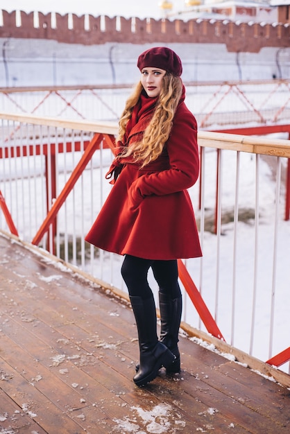 Beautiful girl wearing a red coat and a beret on Christmas street 