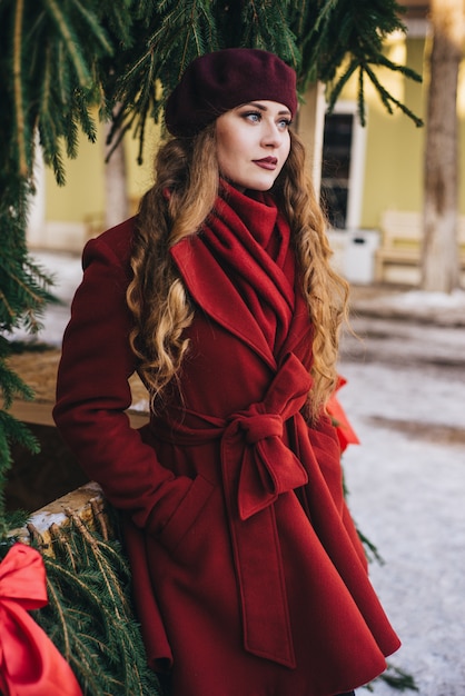 Beautiful girl wearing a red coat and a beret on Christmas street 