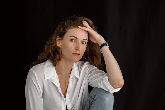 Beautiful girl in white clothes. Portrait of an attractive middle-aged woman in a dark room.