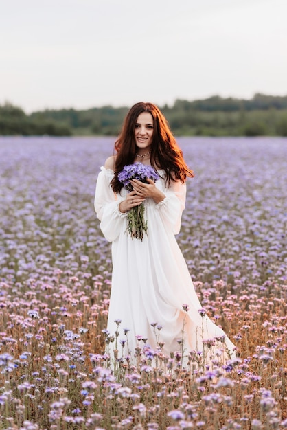 A beautiful girl in a white dress in a blooming field of Provence 