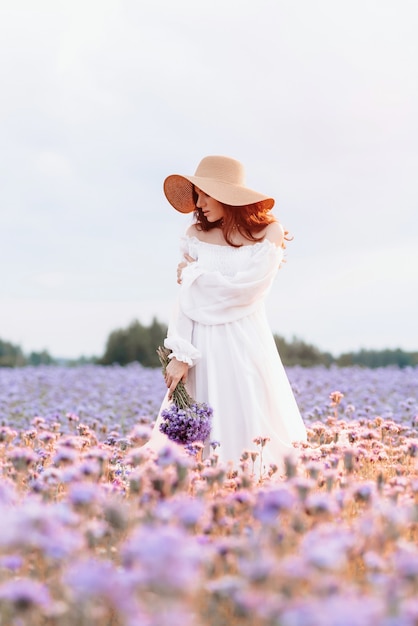 A beautiful girl in a white dress in a blooming field of Provence 