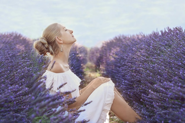 Beautiful girl in a white dress on a lavender field in Provence