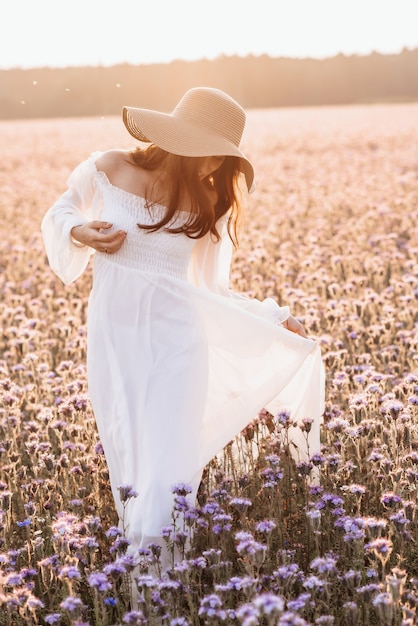 Beautiful girl in a white dress in a lavender field at sunset