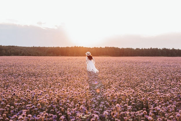 Beautiful girl in a white dress in a lavender field at sunset