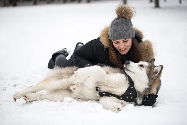 Beautiful girl in winter forest with dog Play with the dog Siberian husky