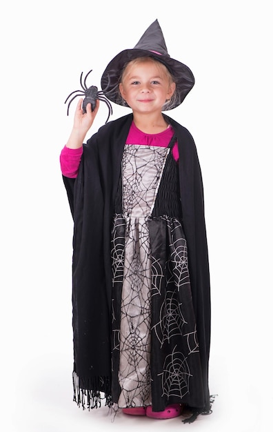 A beautiful girl in a witch costume in a hat with a spider in her hands on a light background copy space The witch waves her magic wand Happy Halloween