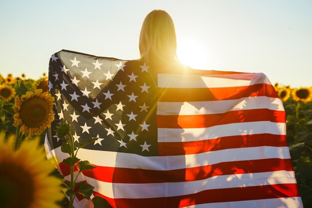 Beautiful girl with the American flag in a sunflower field 4th of July Fourth of July Freedom