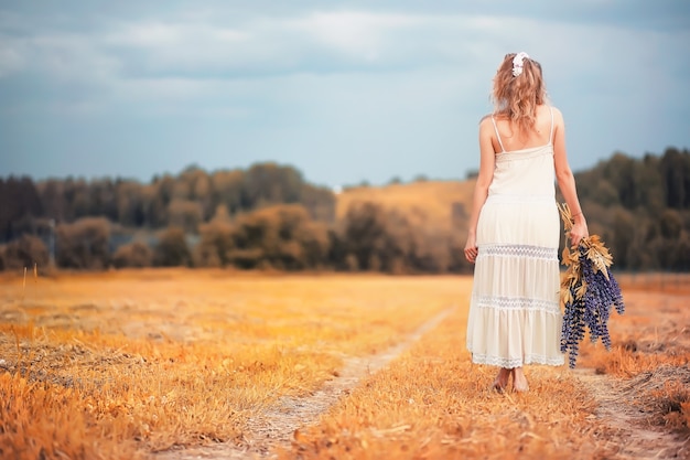 Beautiful girl with a bouquet of blue flowers on nature in autumn