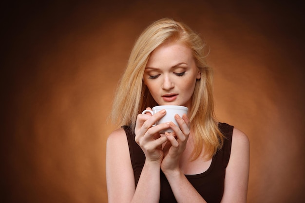 Beautiful girl with cup of coffee on dark background