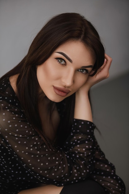 Beautiful girl with dark hair in black clothes posing for a photographer