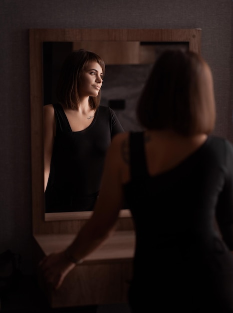 Beautiful girl with dark hair turned her back Reflection in the mirror