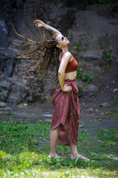 Beautiful girl with dreadlocks dressed hippie styleposes outdoors