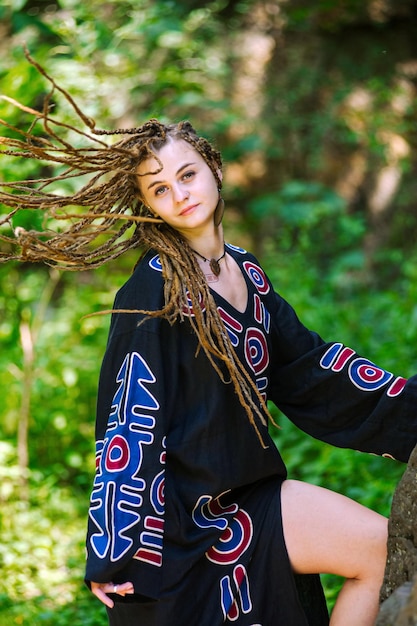 Beautiful girl with dreadlocks dressed hippie styleposes outdoors