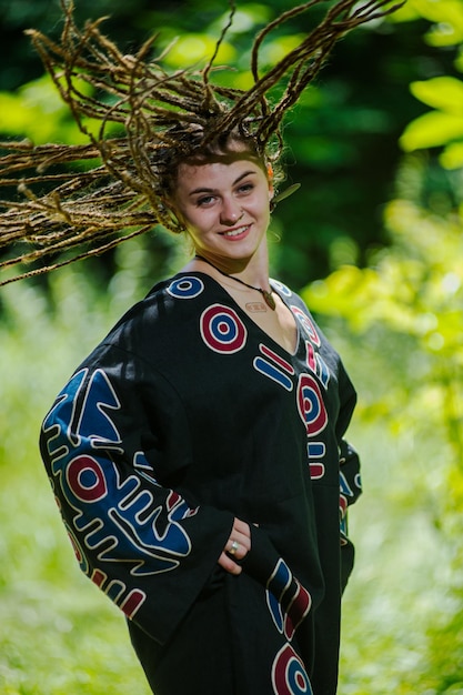 Beautiful girl with dreadlocks dressed hippie styleposes outdoors