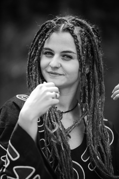 Beautiful girl with dreadlocks dressed hippie styleposes outdoors