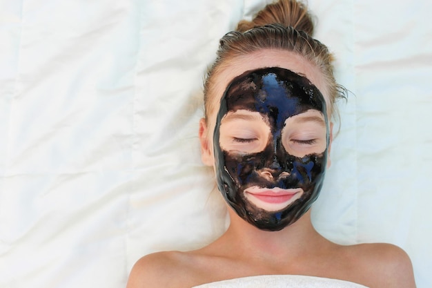 Beautiful girl with facial black clay mask