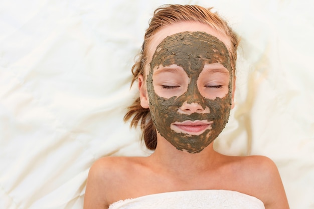 Beautiful girl with facial clay mask. 