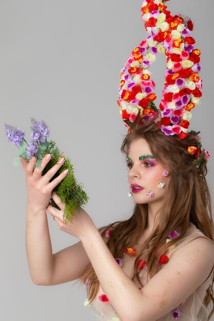 Beautiful girl with flower horns with a bunch of flowers