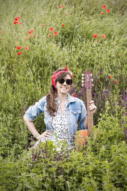 Beautiful girl with a guitar in poppies. 