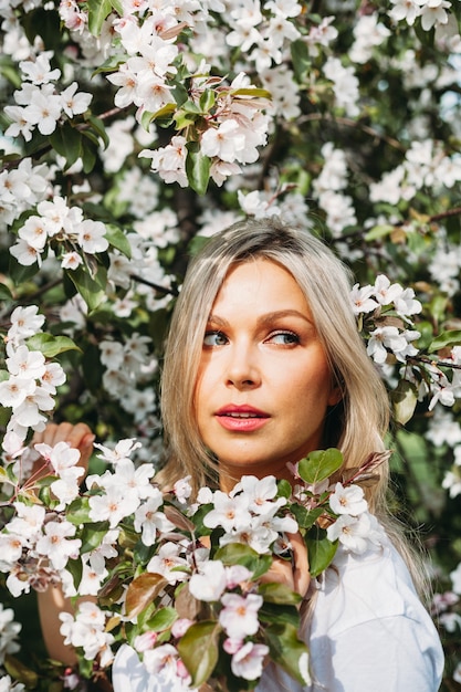 Beautiful girl with light hair, glasses, near flowering trees, Apple tree, spring, branches, flower, fashion, style, European, red