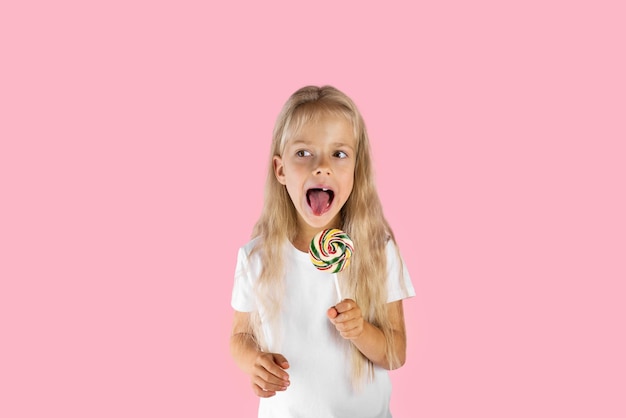 Beautiful girl with a lollipop on a pink background