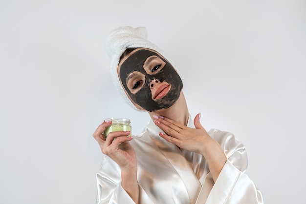 Beautiful girl with mud oy black clay facial mask isolated on white