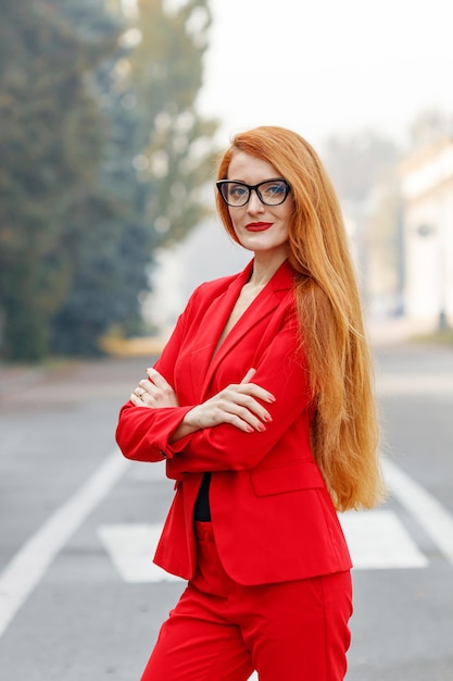 Beautiful girl with red hair dressed in a red business suit Business portrait