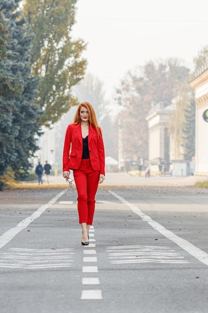 Beautiful girl with red hair dressed in a red business suit Business portrait