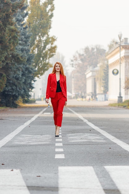 Beautiful girl with red hair dressed in a red business suit Business portrait