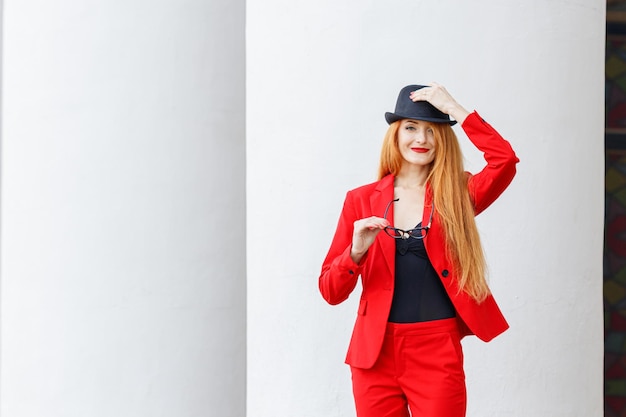 Beautiful girl with red hair dressed in a red business suit Business portrait