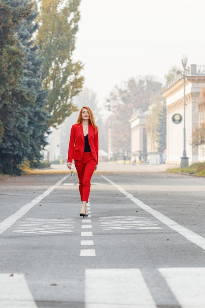 Beautiful girl with red hair dressed in a red business suit Business portrait