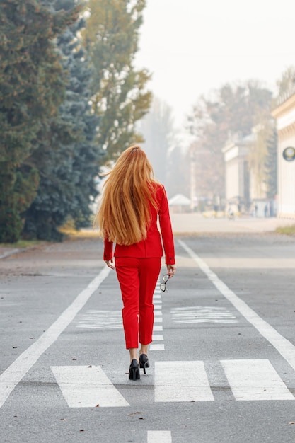 Beautiful girl with red hair dressed in a red business suit Business portrait