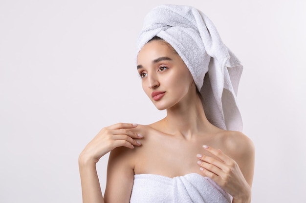 Beautiful girl with thick eyebrows and perfect skin at white background towel on head beauty photo