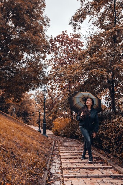 Photo beautiful girl with umbrella at autumn park