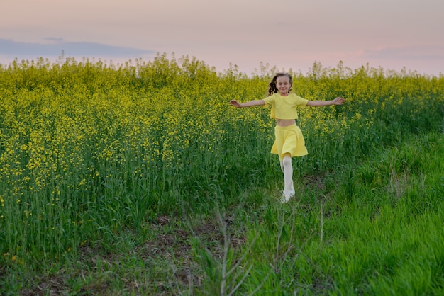 The beautiful girl in a yellow dress on the blossoming field