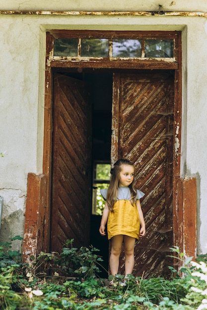 Beautiful girl in a yellow dress near a wooden door