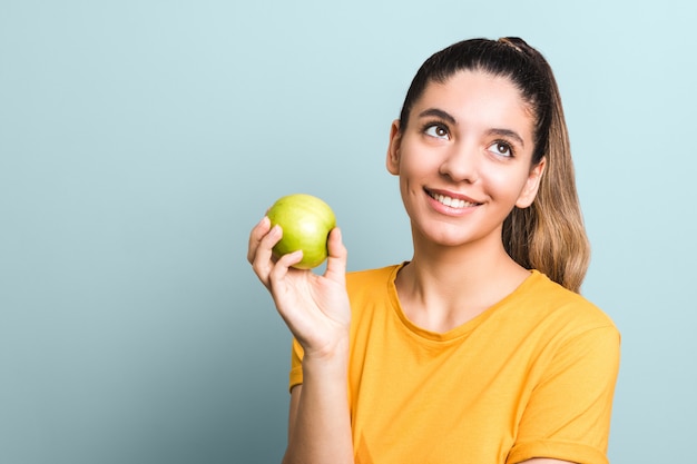 Beautiful girl in yellow t-shirt holding green apple in palm with copy space. idea design