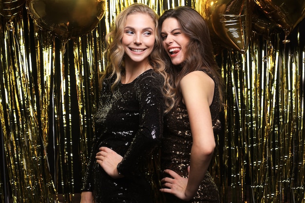 Beautiful girls celebrating New Year. Gorgeous smiling young women enjoying party celebration, having fun together.