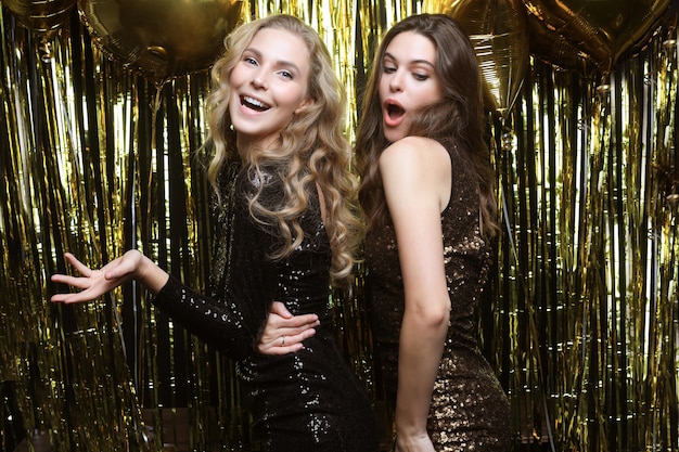 Beautiful girls celebrating New Year. Gorgeous smiling young women enjoying party celebration, having fun together.