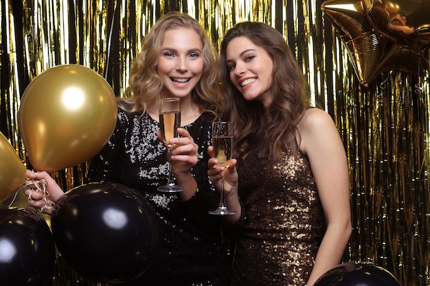 Beautiful girls celebrating New Year. Gorgeous smiling young women enjoying party celebration, having fun together.