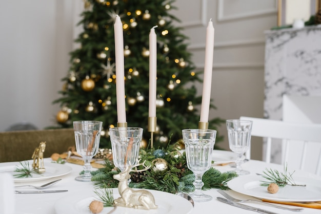 Beautiful glass glasses, candles in the decor of the festive table. Christmas table setting